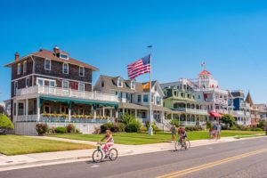 People riding bikes and walking in front of beautiful homes in Cape May, NJ
