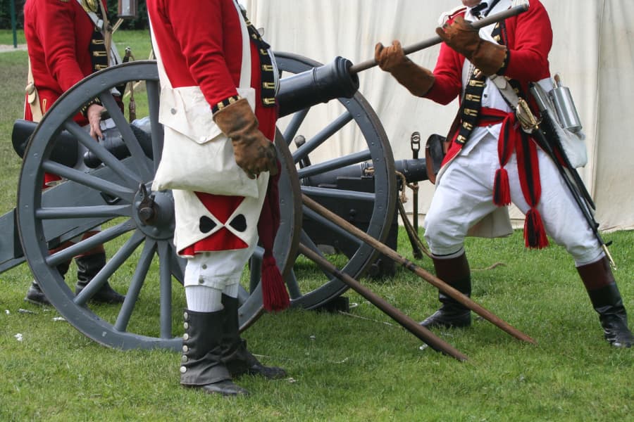 Revolutionary War reenactors in uniforms near cannons