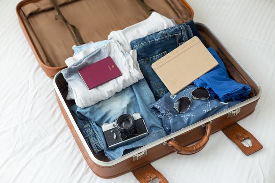 Suitcase packed with vacation essentials, including clothes and camera