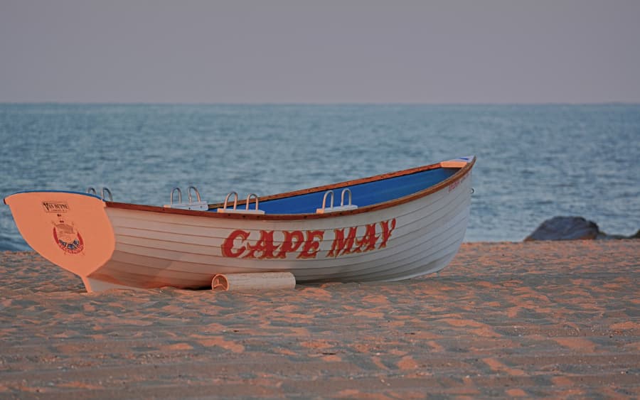 Rowboat with Cape May on side sitting on sand of beach