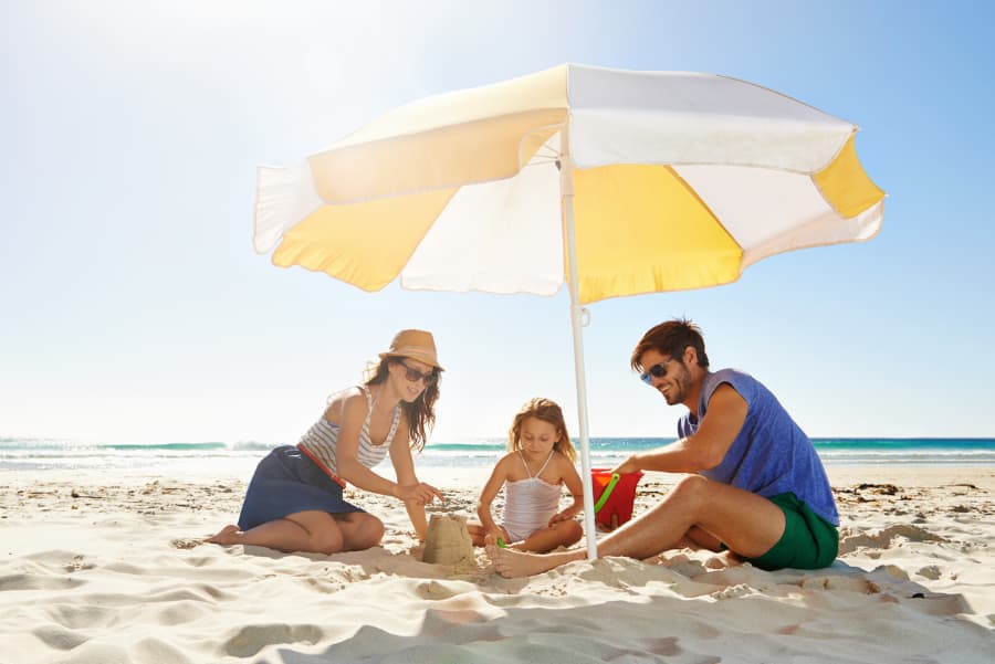 Parents and child build a sandcastle on the beach