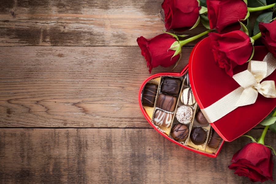 Valentine’s day box of chocolates and red roses on wood background