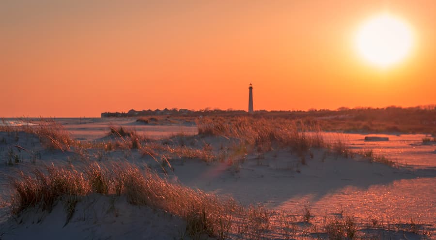 Sunset on beach with lighthouse in background