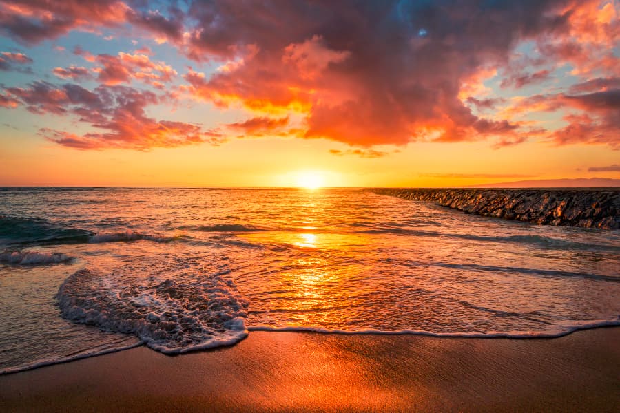 View of setting sun and clouds from beach