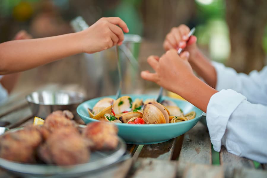 Two children serving up seafood from serving dish outside