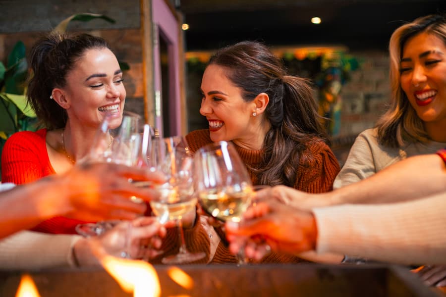 Friends laughing while toasting at cocktail bar